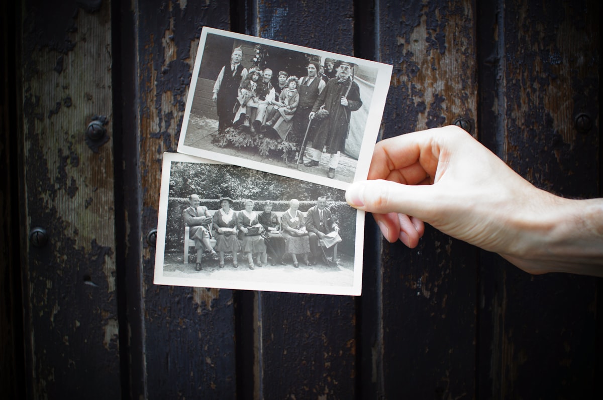 A hand holding two old black and white photographs